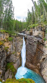Breathtaking waterfall cascading into a vibrant turquoise pool amid the rugged beauty of johnston