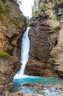 Breathtaking waterfall cascading into a vibrant turquoise pool, surrounded by rugged cliffs and