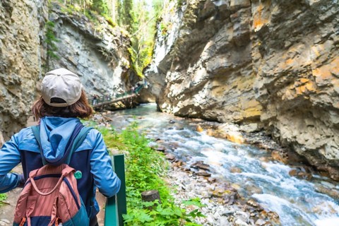Female tourist with a backpack admiring the turquoise waters of bow river flowing through johnston