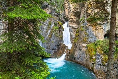 Turquoise water flows through johnston canyon in banff national park, creating a picturesque scene