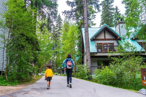 Mother and son walking away on a paved path near the emerald lake lodge in banff national park,