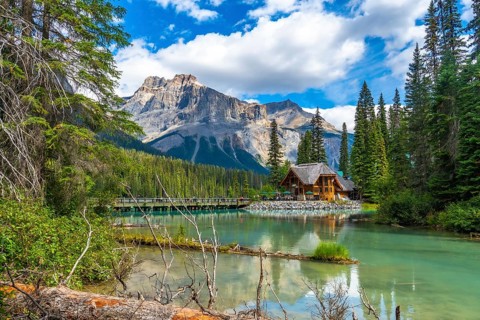 Wooden lodge reflecting in turquoise water with president range mountains towering behind and