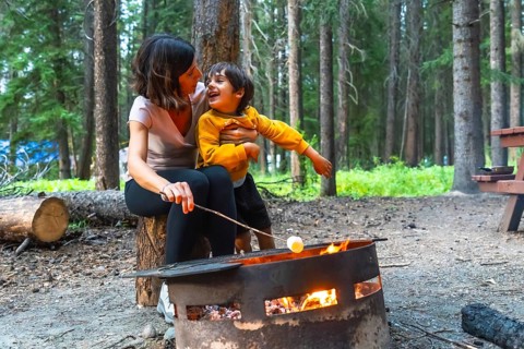 Mother and son are roasting marshmallows over a campfire in banff national park, alberta, canada,