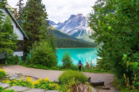 Tourist with a backpack is enjoying the breathtaking view of the turquoise waters of emerald lake,