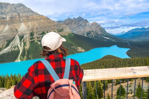Female hiker enjoying breathtaking view of turquoise peyto lake and surrounding mountains in banff