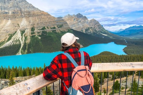 Young hiker admiring stunning turquoise color of peyto lake from viewpoint in banff national park,