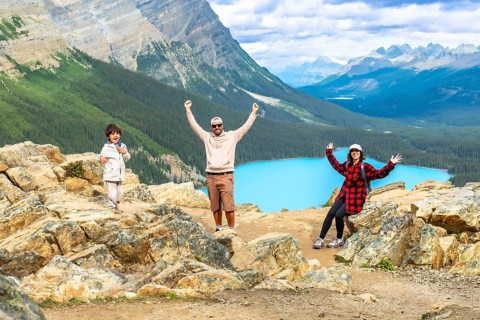 Tourists raising their arms in excitement while admiring the stunning turquoise peyto lake from a