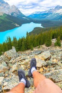 Hiker resting on rocky terrain while enjoying breathtaking views of turquoise peyto lake,