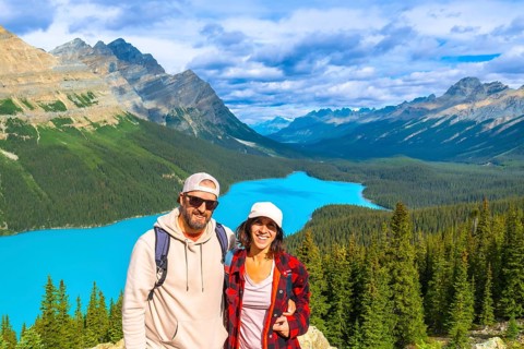 Two hikers enjoying the breathtaking panoramic view of turquoise peyto lake, surrounded by the