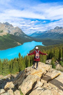 Female hiker with a backpack standing on a rocky cliff, enjoying the stunning panoramic view of