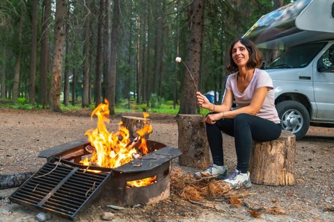 Female tourist roasting marshmallows over a campfire in a campground in banff national park, next