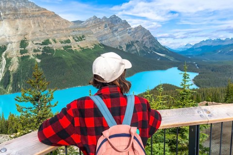 Female tourist with backpack and baseball cap enjoying breathtaking panoramic view of turquoise