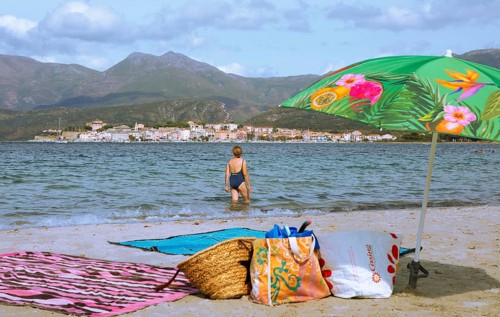 Sunshade and swimwear blurred on the beach or Plage de la Roya, in the back Saint-Florent on the