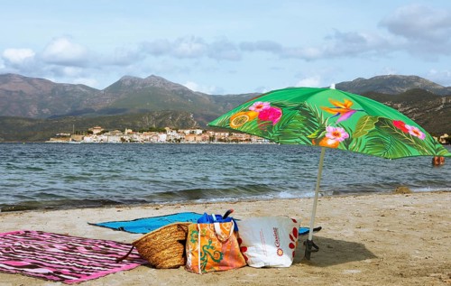 Sunshade and swimwear on the beach or Plage de la Roya, in the back Saint-Florent on the Gulf of