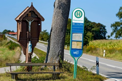 MVV bus stop at traditional crossroads, wayside cross, bench and oak (Quercus) between fields,