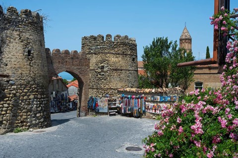 Historic stone gate with stalls and flowers in the foreground, city gate, entrance to the old town,