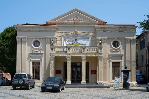Neoclassical theatre building with columns and cars in the foreground on a sunny day, theatre,