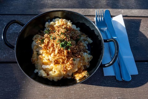 Typical food on an alpine pasture, a portion of cheese patzen or cheese socks in a cast pan,