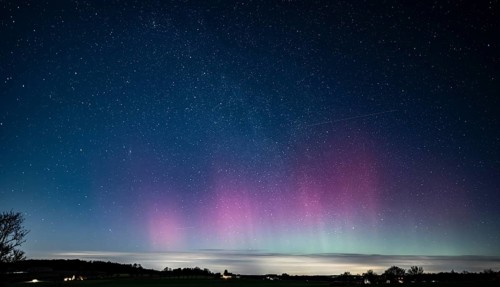 Glowing polar lights in shades of purple and green under a clear starry sky, EXPO Observatory