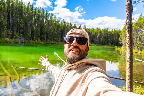 Happy tourist taking a selfie with outstretched arms, embracing the stunning turquoise waters of