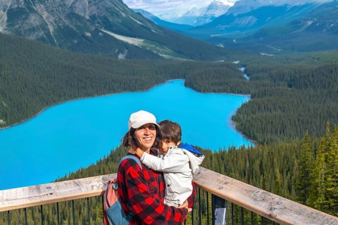 Mother holding her son while admiring the stunning turquoise waters of peyto lake, surrounded by