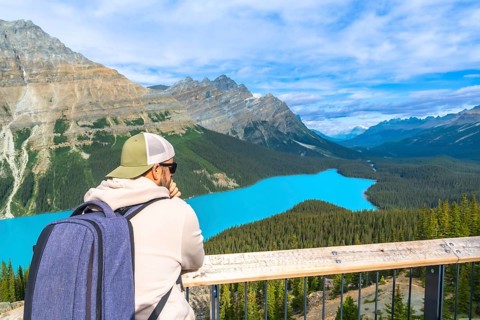 Tourist with backpack is enjoying the breathtaking panoramic view of the turquoise peyto lake and