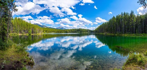 Breathtaking panoramic view of pristine herbert lake reflecting a vibrant blue sky with fluffy