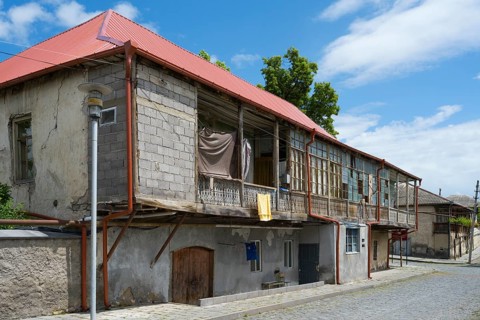 An old, rustic building with a dilapidated state and wooden veranda under a clear blue sky,