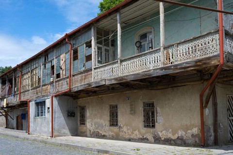 Elongated balcony of an old building with weathered wooden railings under a clear blue sky,