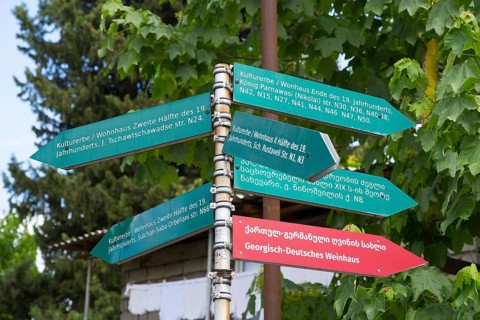 Colourful guide with cultural heritage signs in German and Georgian under Laub, Bolnissi,