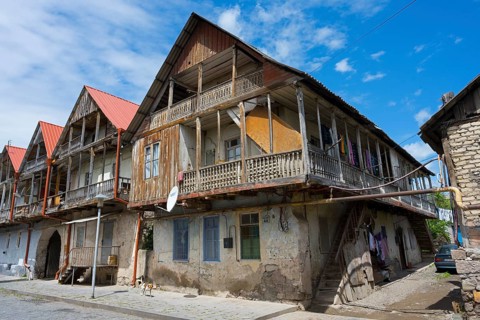 Historic wooden house with veranda under a blue sky, showing traditional architecture, traditional
