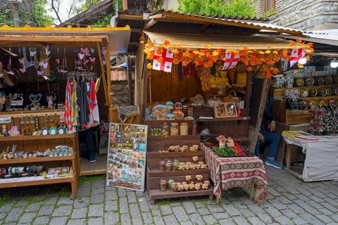 Market stalls with handmade souvenirs and decorations surrounded by flags and autumn leaves,