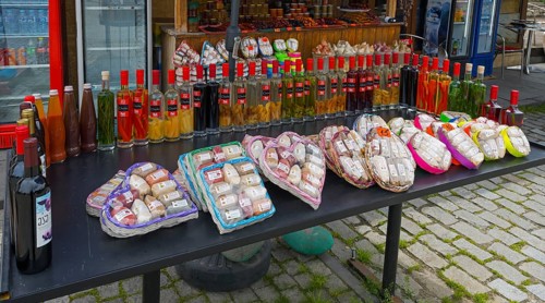 Diverse selection of spices and bottles at a traditional market stand, chacha with colorful fruits,