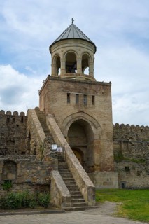 A bell tower with stone steps and fortress under a cloudy sky, Svetitskhoveli Cathedral,