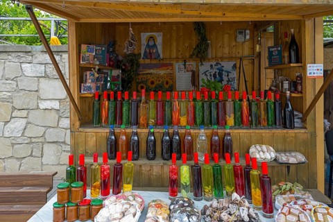 Market stall with various colorful bottles, food and souvenirs on a table, chacha with colorful