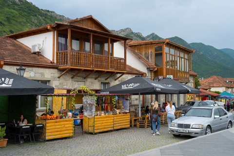 Cosy marketplace with cafes and shops framed by mountains under a cloudy sky, houses on Mtskheta