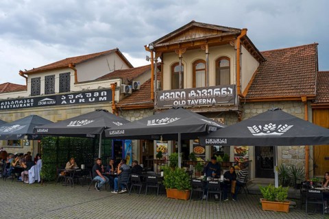 A cozy tavern with outdoor seating and lots of umbrellas, ideal for social gatherings, houses on