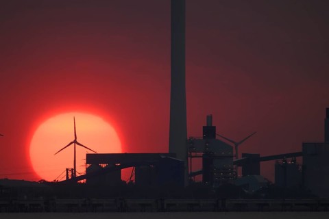 Sunset behind industry and wind turbines, near Jade-Weser Port, intense red in the sky View over
