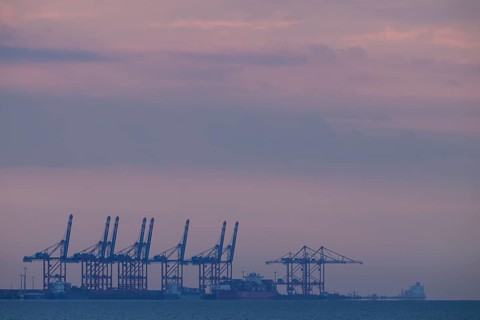 Cranes container bridges at Jade.Weser Port against a purple evening sky, calming atmosphere,