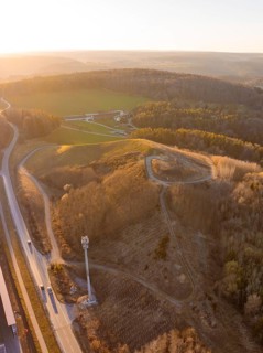 Hilly landscape with roads and dense forest in the light of sunset, future PV building on old