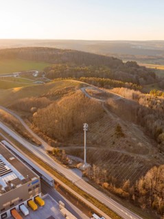 Hilly landscape with forest and telecommunications tower at sunset, future PV building on old