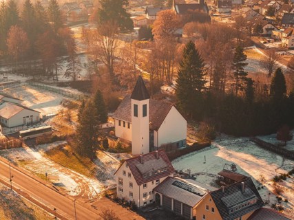 Close-up of a church in a small, snowy village surrounded by trees and a peaceful ambiance,