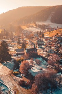 Idyllic view of a village with a central church surrounded by snow-covered houses and hills,