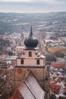 View of a church tower in front of a snow-covered city panorama with vast fields, Herrenberg,