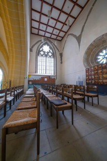 Church interior with rows of chairs and Gothic windows, quiet and devotional atmosphere, collegiate