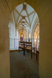 View through an arch of seats in a church with Gothic arches, quiet atmosphere, collegiate church,