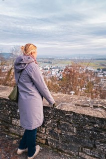 Woman in a coat looking out over a quiet winter landscape with a wide view, Herrenberg, Böblingen