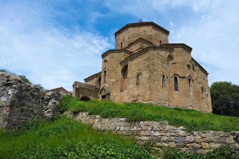 Stone church with grass-covered wall under blue sky, Javari Monastery, Jvari Monastery, Dzhwari