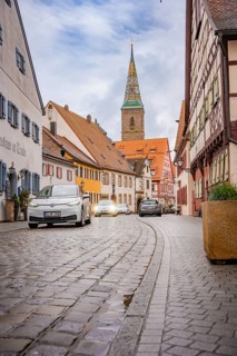 Narrow paved alley in historic old town with church tower, ID3, deer e-car sharing, Germany