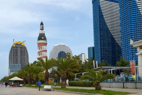 A mix of modern skyscrapers and a round tower offers a contrasting city view under cloudy sky,